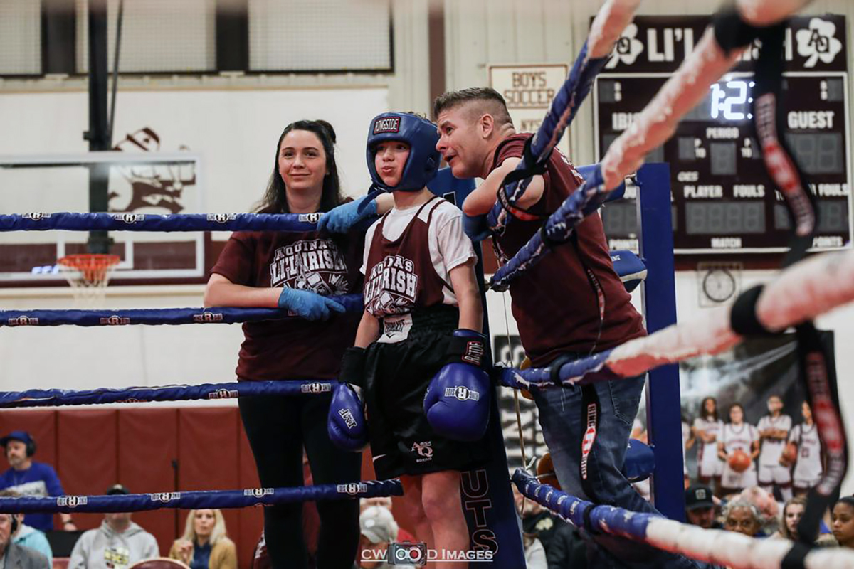 Aaron Hilton (Class of 2031) with coaches Aarika Miller (Class of 2014) and Coach Mike Quinlan (Class of 95) gets ready to enter the ring as part of the Aquinas Institute boxing program in Rochester, New York.